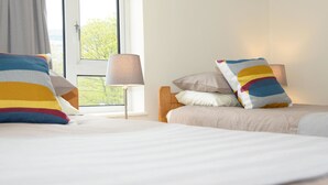 A hotel room with two beds, a window with a view, and a lamp. - Gallt y Glyn (Caernarfon)