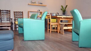 A cozy living room with teal armchairs, a wooden coffee table, and a bookshelf. - Gallt y Glyn (Caernarfon)