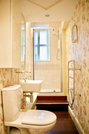 A bathroom with a toilet, sink, shower, and a small window. - Period Property on Castle Street (Edinburgh)