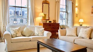 A living room with two sofas, a wooden coffee table, a mirror, and a lamp.
