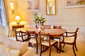 A dining area with a round table, six wooden chairs, a vase of flowers, and a lamp. - Period Property on Castle Street (Edinburgh)