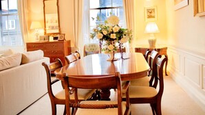 A dining room with a wooden table, chairs, a vase of flowers, a mirror, and a dresser.