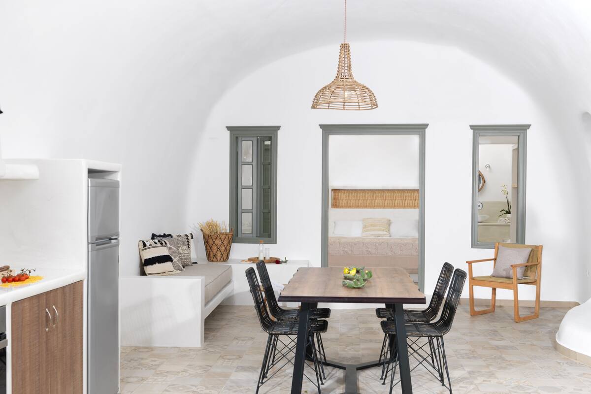 A compact, modern kitchen with a dining area, a built-in bench, and a large mirror.