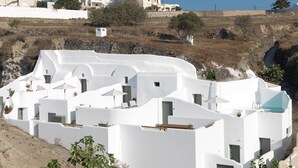 A white-washed building with multiple rooms, a small garden, and a view of the surrounding landscape. - Drops Cave Houses (Santorini)