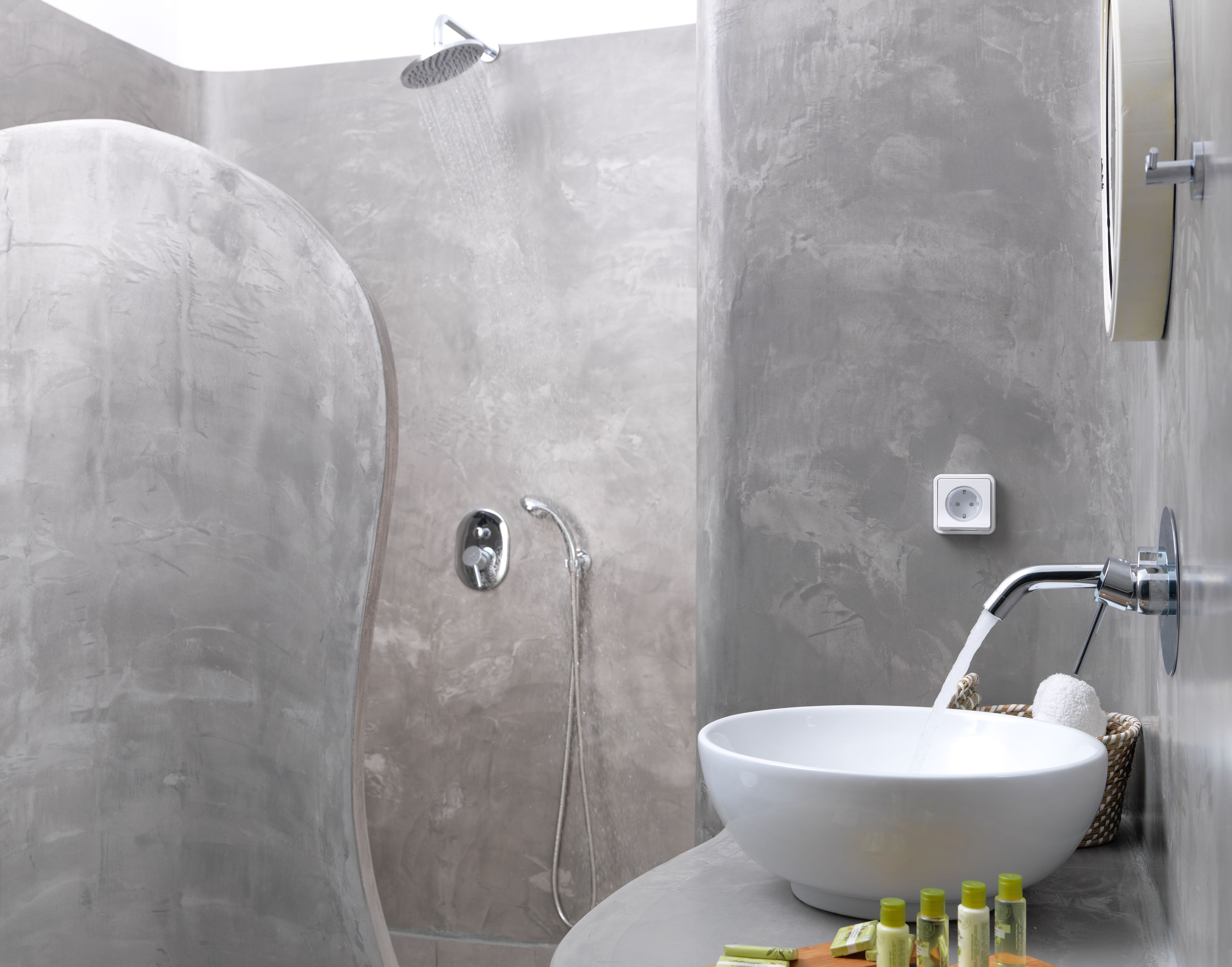 A modern bathroom with a large white basin, a shower, and a small sink.