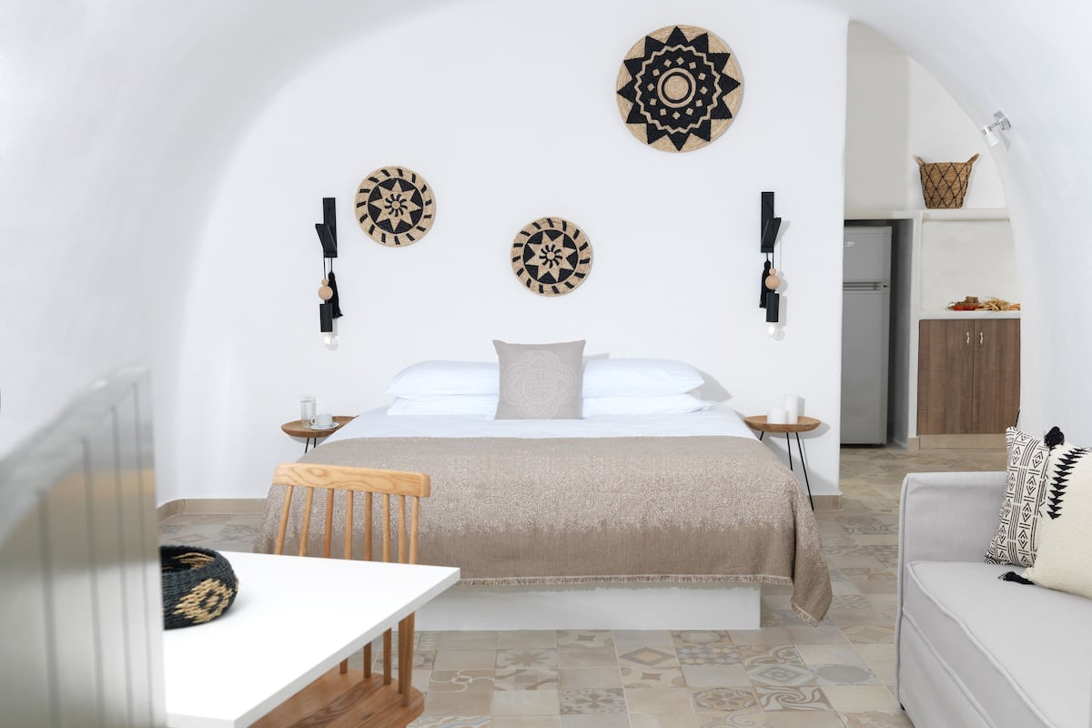 A bedroom with a bed, bedside tables, a chair, a sofa, and decorative wall hangings.