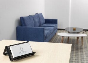 Ein Zimmer mit einem blauen Sofa, einem kleinen runden Tisch und einer Tafel mit dem Wort 'drops'.
