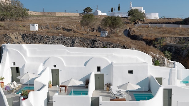 A white villa with a pool, multiple rooms, and a view of the surrounding landscape. - Drops Cave Houses (Santorini)