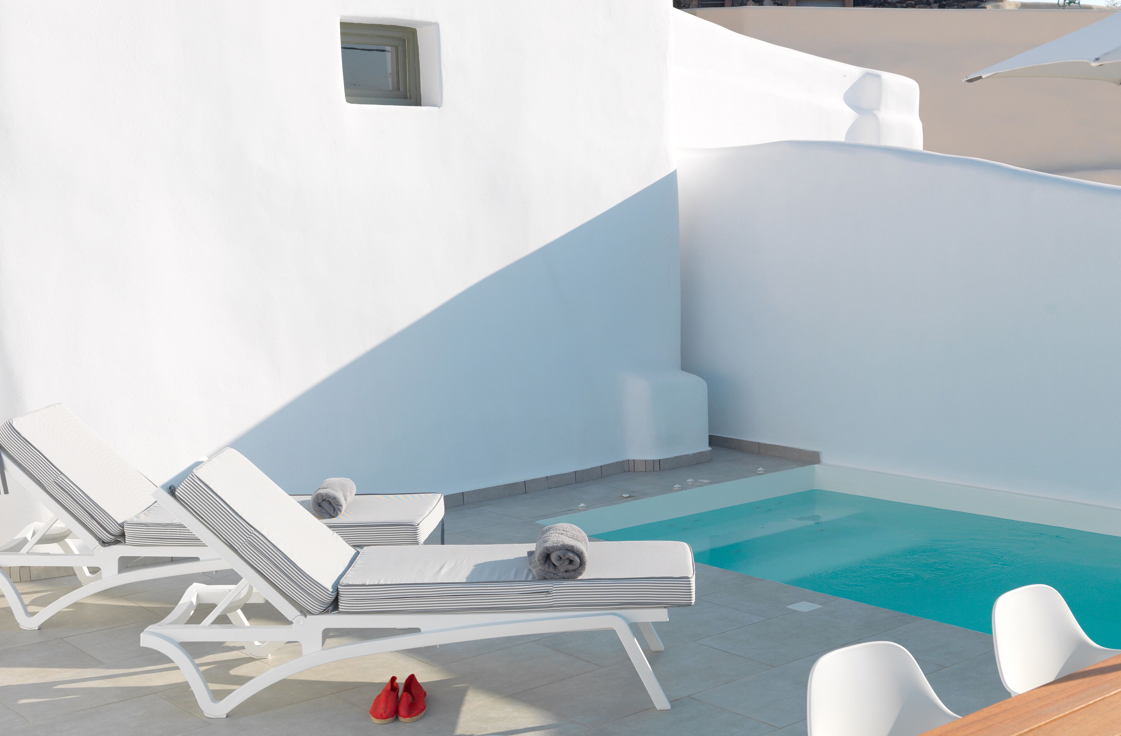 Ein Poolbereich mit weißen Liegestühlen und einem kleinen Pool.
