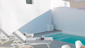 Ein Poolbereich mit weißen Liegestühlen und einem kleinen Pool.