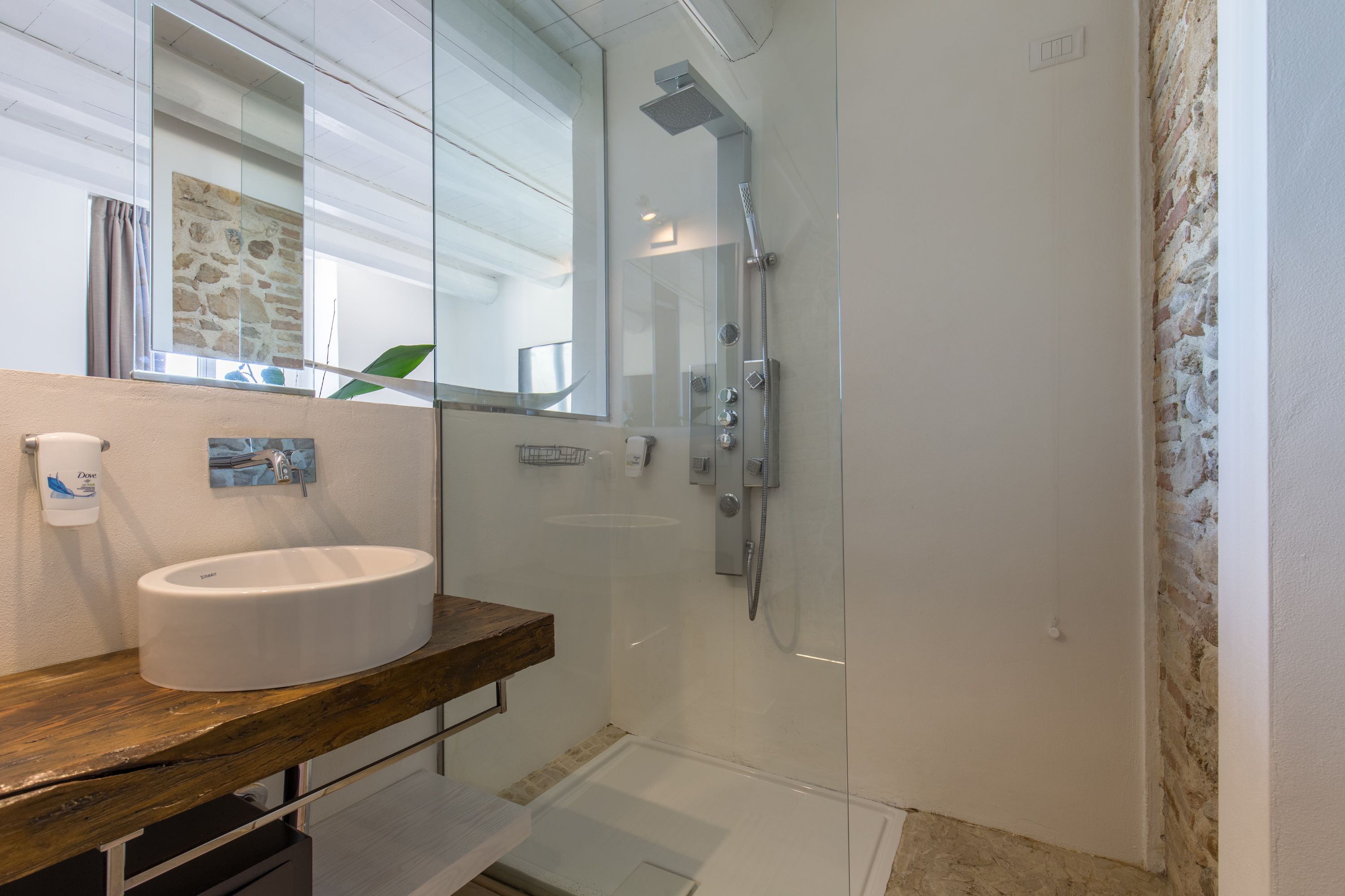 A bathroom with a glass-enclosed shower, a white sink, and a wooden countertop.