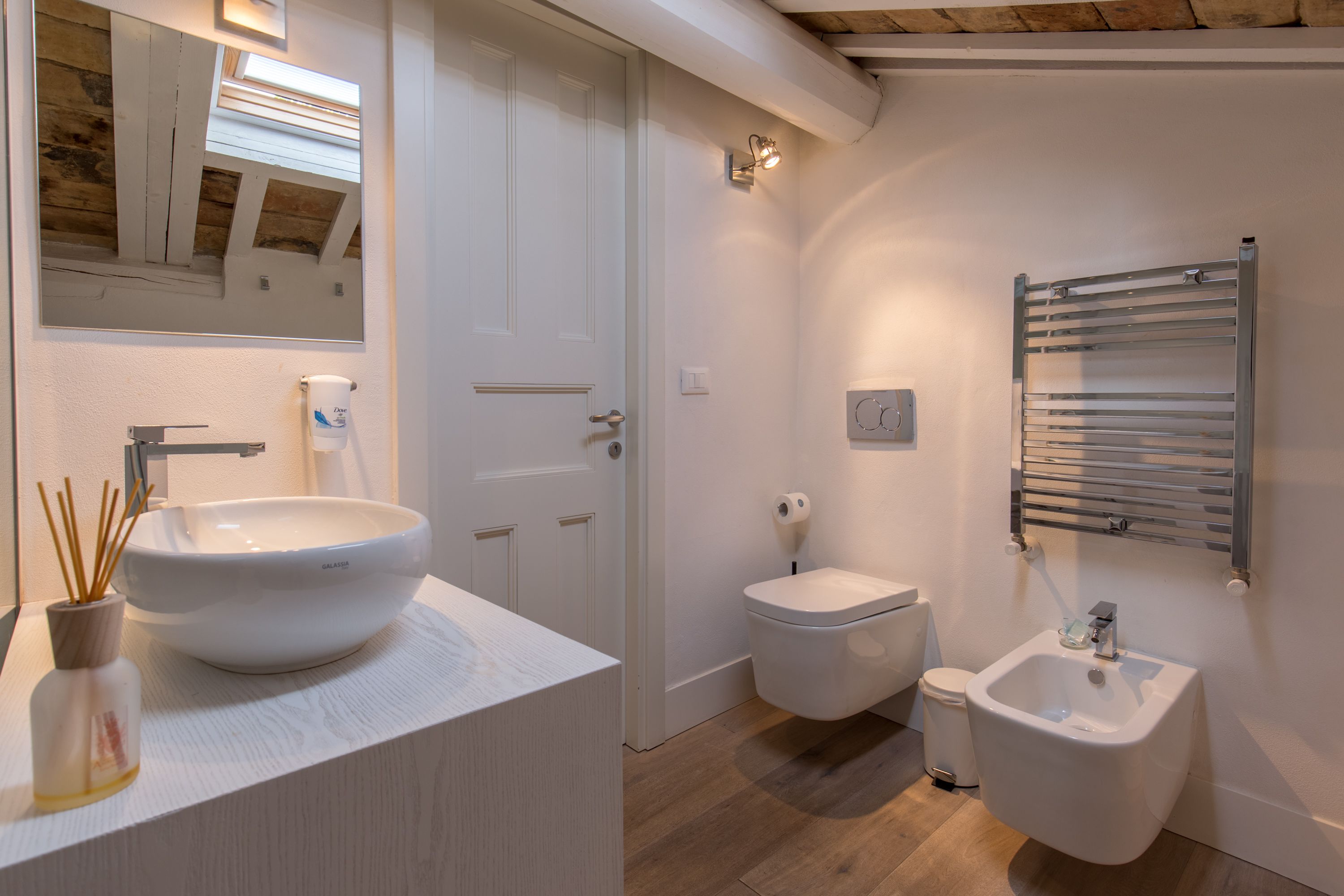 A modern bathroom with a large white sink, a bidet, and a small pedestal sink.