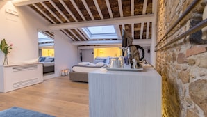 Un loft moderne avec des poutres apparentes, une verrière, un coin salon confortable et un comptoir de cuisine intégré.