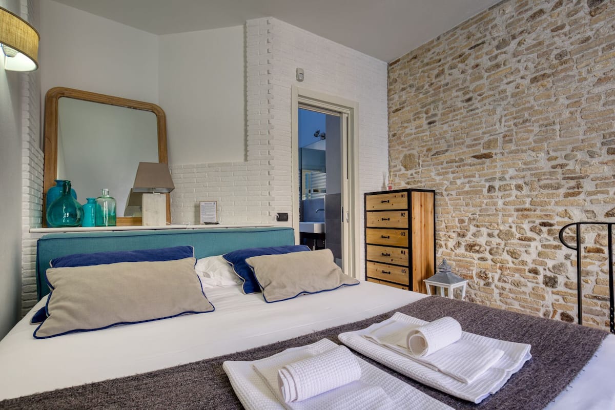 Ein Schlafzimmer mit einem Bett, einem Schminktisch, einem Spiegel und einer Steinwand.