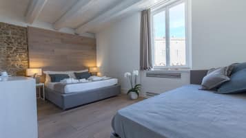 Una camera da letto moderna con un letto grande, un letto più piccolo, una scrivania e un muro in pietra.