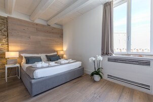 Camera da letto moderna con un letto, lampade sui comodini, una pianta in vaso e una finestra con tende.