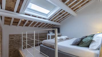 Une chambre de style loft avec une lucarne, un lit superposé et une table de chevet avec une lampe.