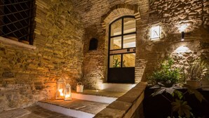 Un intérieur aux murs de pierre, agrémenté d’un banc, de lanternes et de plantes en pot.