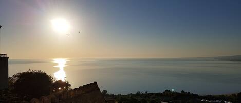 Vista sulla costa con un'antica muraglia in pietra e cielo sereno.
