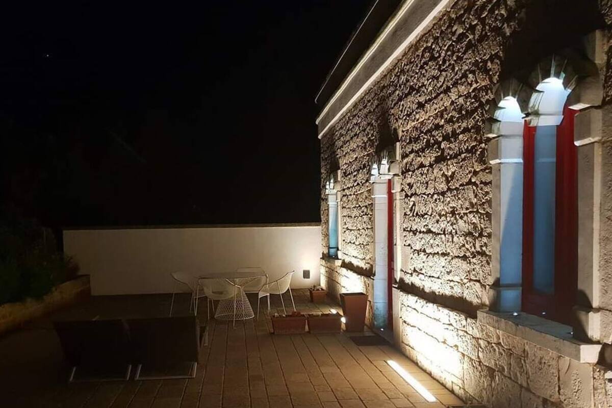 An outdoor patio area with a stone wall, a table with chairs, and a small seating area.