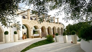 Un patio con un edificio de piedra que presenta arcos y una zona de estar.