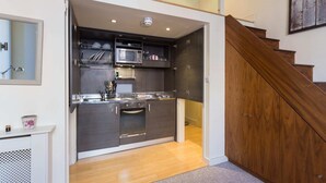 Eine kompakte Küche mit modernen Geräten, einer Holztreppe und einem kleinen Essbereich.