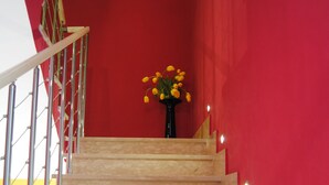 A staircase with a red wall and a vase of yellow flowers at the top.