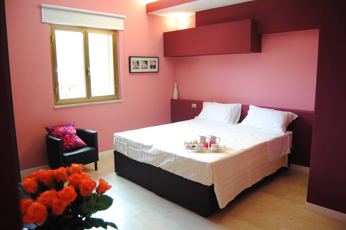 Quarto com cama, cadeira e janela.