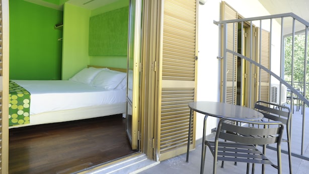 A room with a bed, a table, and chairs, and a staircase leading to an outdoor area.