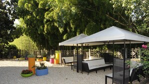 An outdoor seating area with two white canopies, wicker furniture, and potted plants.