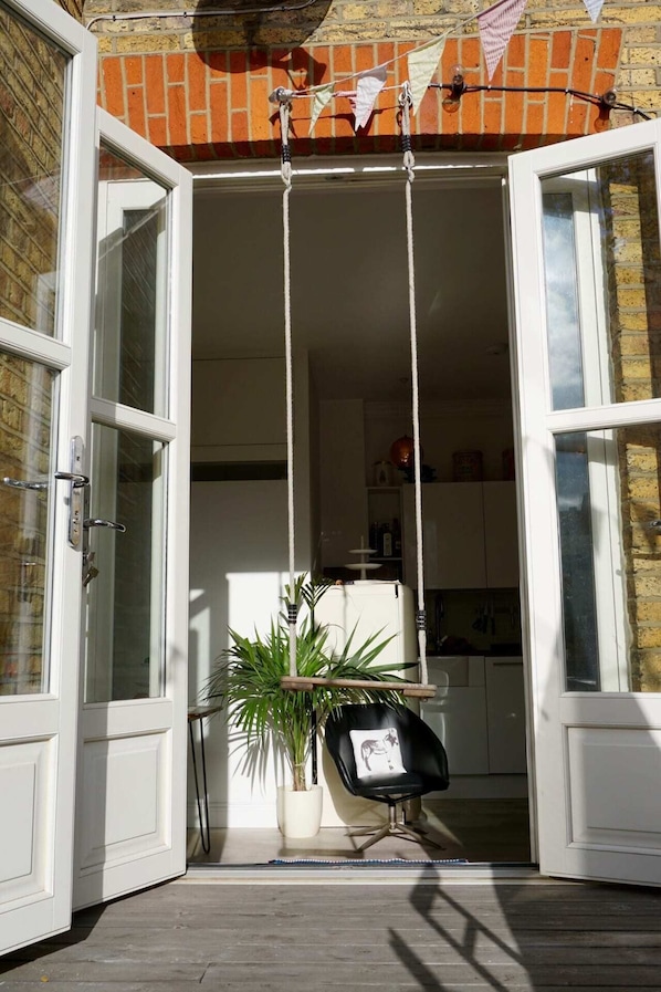 An open door leading to a kitchen with a potted plant and a black chair.