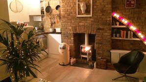 Una habitación acogedora con chimenea de ladrillo, una silla negra y una planta.