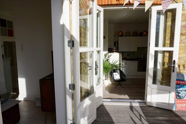 An open door leading to a kitchen with a dining area, a potted plant, and a chair. - Beautiful Canalside 1-bedroom Flat With Terrace (London)