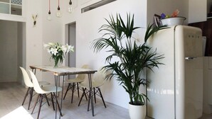 Un comedor con una mesa, sillas, una planta en maceta y un refrigerador.