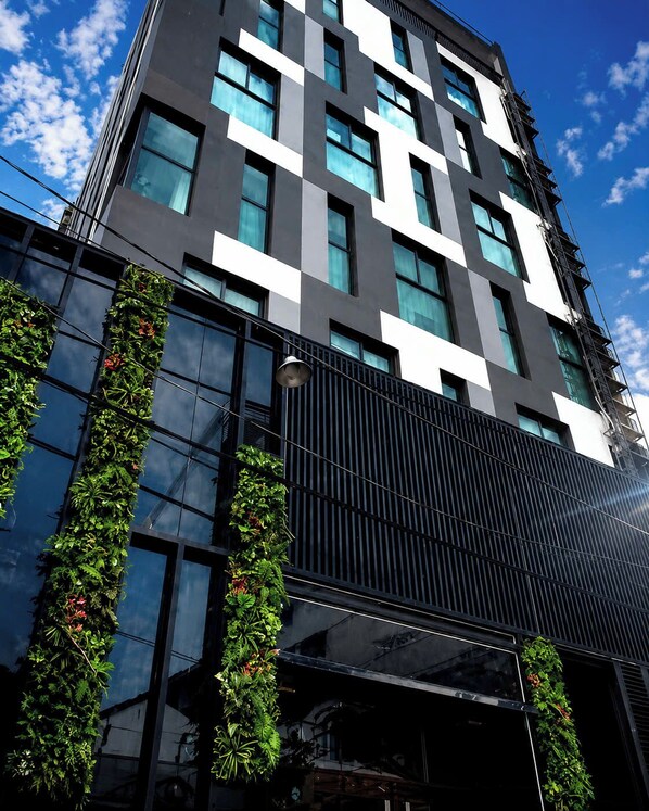 A modern building with a checkered facade, large windows, and vertical greenery. - Sena Botanic (Ho Chi Minh City)