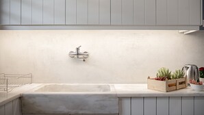Cozinha com pia grande, bancada de madeira e painel atrás da pia.