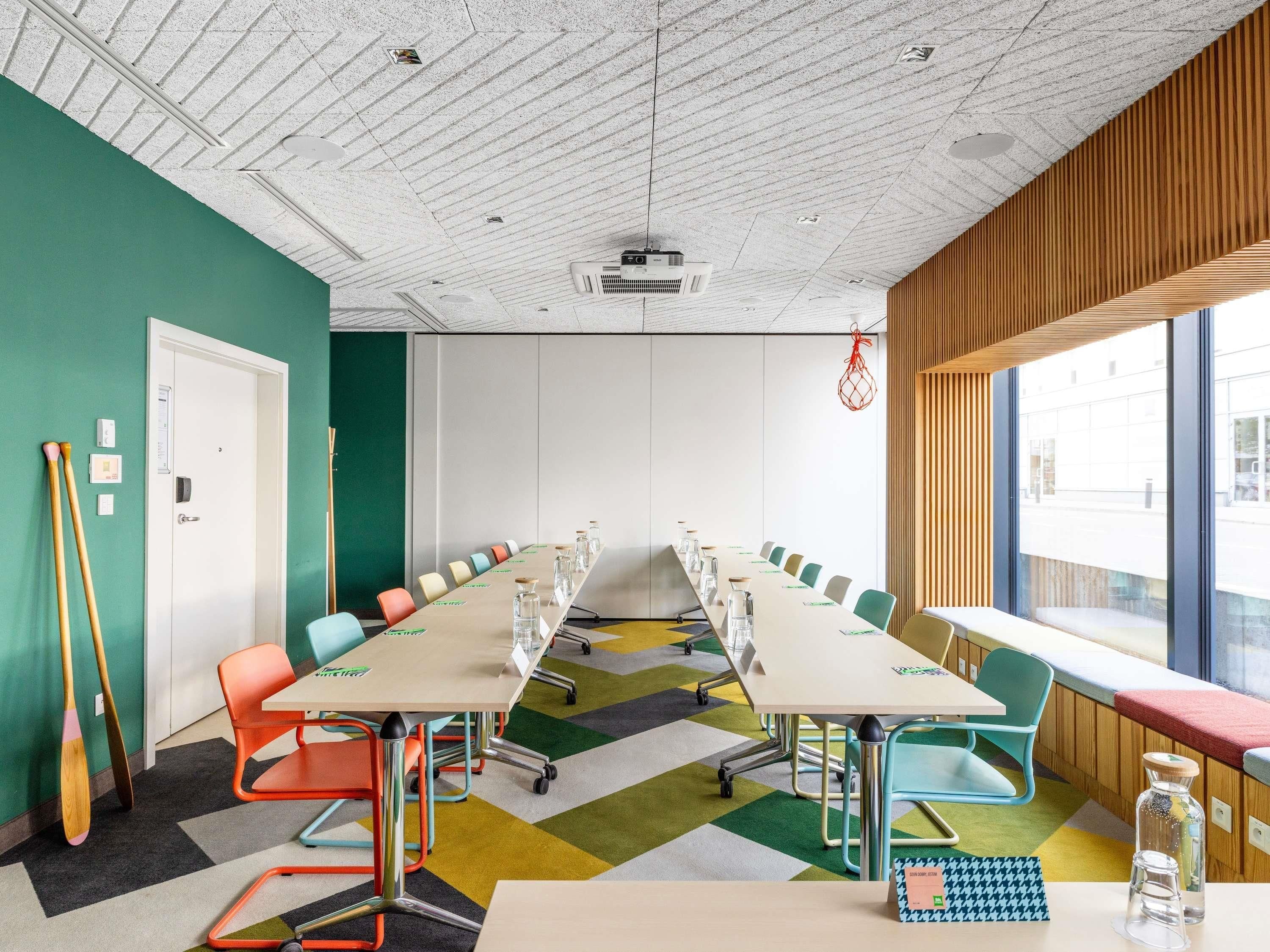 A conference room with a long table, colorful chairs, a whiteboard, and a basketball hoop.