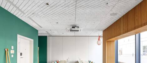 A conference room with a long table, colorful chairs, a whiteboard, and a basketball hoop.