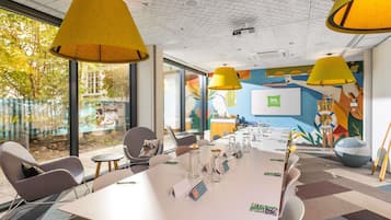 A conference room with a white table, multiple chairs, and yellow lamps.