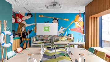 Un salón de conferencias con un mural colorido, un proyector y una mesa con tarjetas de nombre.