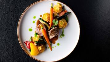 A plate of food with various vegetables and a piece of meat, served on a white plate with a brown rim.
