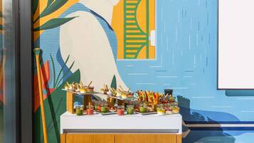 Un bufé con diversos alimentos y utensilios sobre una barra frente a una pared colorida.