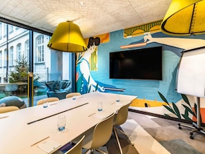 A modern meeting room with a large table, chairs, a TV, and a mural. - ibis Styles Warszawa Centrum (Warsaw)