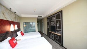 Een hotelkamer met twee bedden, een minibar, een televisie en een muur met een geometrisch ontwerp.