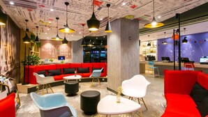 Een moderne lounge met rode zitplaatsen, zwart-witte tafels en hanglampen.