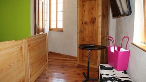 A room with a wooden bench, a small table, a cabinet, and a television mounted on the wall. - Hotel Turmdieb (Volkach)
