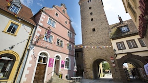 A historic building with a prominent tower, a cafe, and a hotel. - Hotel Turmdieb (Volkach)