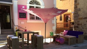An outdoor seating area with a table and chairs, a pink umbrella, and a building with a sign that reads "KAFFEEHAUS". - Hotel Turmdieb (Volkach)