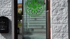 Entrada de un edificio moderno con puerta de cristal y un logotipo circular verde.