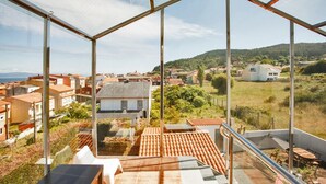 Una habitación moderna con paredes de vidrio y vista a un pueblo en la ladera de una colina.